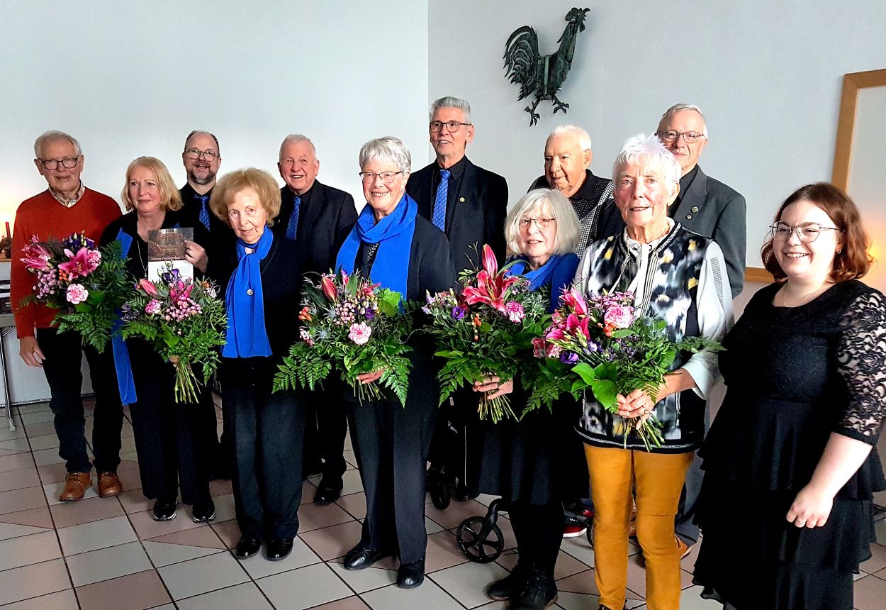 Mit Sängerinnen und Sängern, die Grund zum Feiern haben, freuen sich Chorleiter und Vorstandsmitglieder.